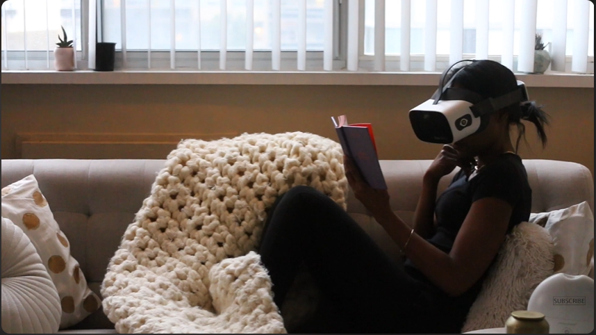 Alisha wearing her Vision Buddy VB4 Max headset, curled up on the couch reading a book