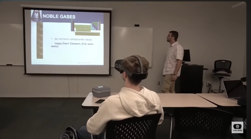 James Warnken wearing his Vision Buddy headset in a college classroom, looking at a projected lesson